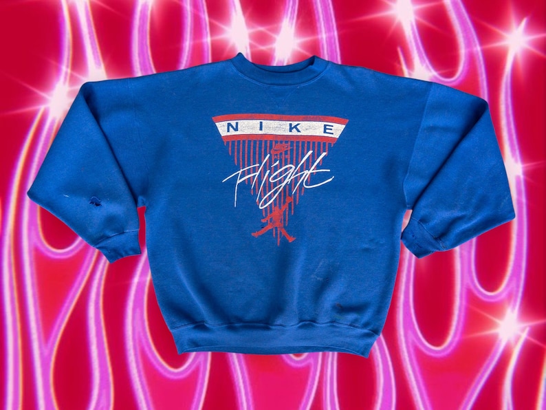 May include: A blue sweatshirt with a red, white, and blue Nike Flight logo. The logo features a basketball player in silhouette and the word "Flight" in a stylized font.