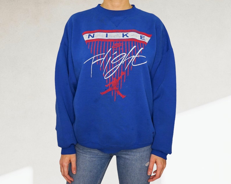 May include: A royal blue sweatshirt with a white and red Nike Flight graphic. The graphic features a basketball player in silhouette and the word "Nike" in a white and red banner.