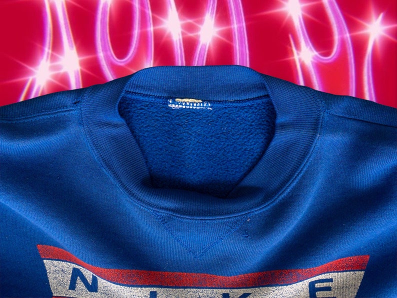 May include: A blue sweatshirt with a white and red logo that says "NIKE" on the front. The sweatshirt has a crew neck and is made of a soft, comfortable material.