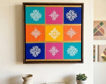 Puede incluir: Obra de arte cuadrada con nueve cuadrados coloridos en turquesa, rosa, naranja, amarillo y azul. Cada cuadrado presenta un diseño blanco intrincado. La obra está enmarcada en madera oscura con un borde interior dorado. En una pared blanca.
