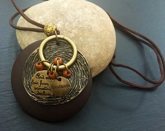 May include: A brown wooden pendant necklace with a brass charm that says "Handmade" and "And on fair from sometime declines". The charm is decorated with small orange beads.