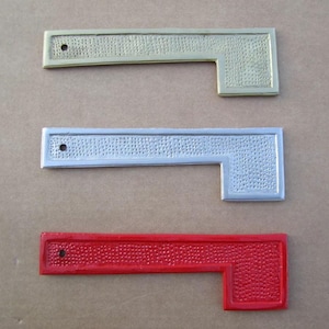 May include: Three mailbox numbers, one gold, one silver, and one red. Each number is a metal plaque with a raised, textured surface.