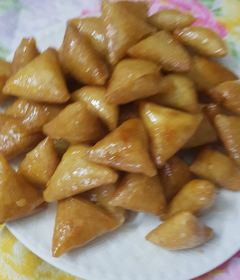 May include: A plate of golden brown, triangular shaped pastries covered in a shiny glaze.