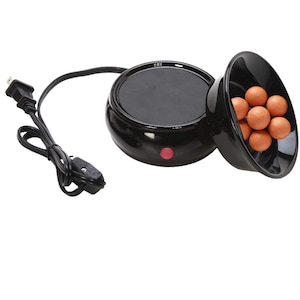 May include: A black electric wax warmer with a circular heating base featuring a small red power indicator light. A black power cord with a plug is attached. Next to the base is a black bowl containing several small, round, light brown wax melts.