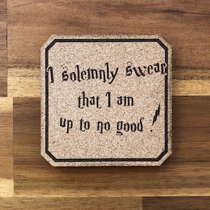 May include: A cork coaster with a black border and the text "I solemnly swear that I am up to no good." in a black font.