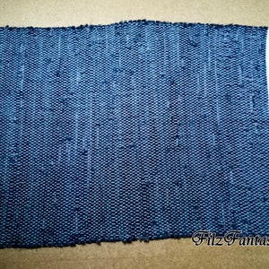 Könnte beinhalten: Ein blauer gewebter Teppich mit weißen Kanten. Der Teppich ist aus recyceltem Denim gefertigt und hat eine strukturierte Oberfläche. Der Text "Filz Fantasien" ist in der rechten unteren Ecke sichtbar.