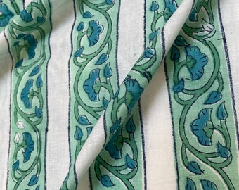 May include: White fabric with green and blue floral stripes. The fabric is folded in half, showing the pattern on both sides.