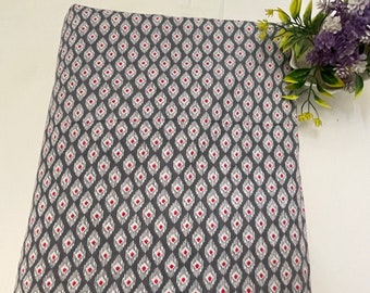 May include: Gray fabric with a white and pink geometric pattern. The pattern is a repeating diamond shape with a small red dot in the center.