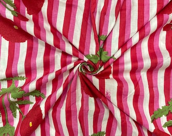 May include: Pink and white striped fabric with a red floral print. The fabric has a white background with pink and red stripes and a repeating pattern of red flowers with green leaves.