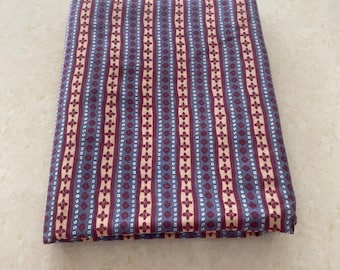 May include: A folded piece of fabric with a striped pattern in shades of blue, pink, and white. The fabric has a small geometric design.