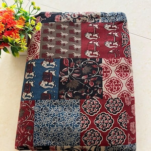 Könnte beinhalten: Ein gefaltetes Textil mit einem Patchwork-Design aus verschiedenen Druckmustern. Der Stoff zeigt Motive von Elefanten, Blumenarrangements und geometrischen Formen in einer Farbpalette aus Dunkelrot, Marineblau, Schwarz und Beige auf dem gesamten Stück.