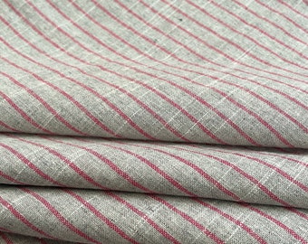 May include: Close-up of a gray and pink striped fabric with a subtle texture. The fabric is folded in several layers, showcasing the pattern and weave.