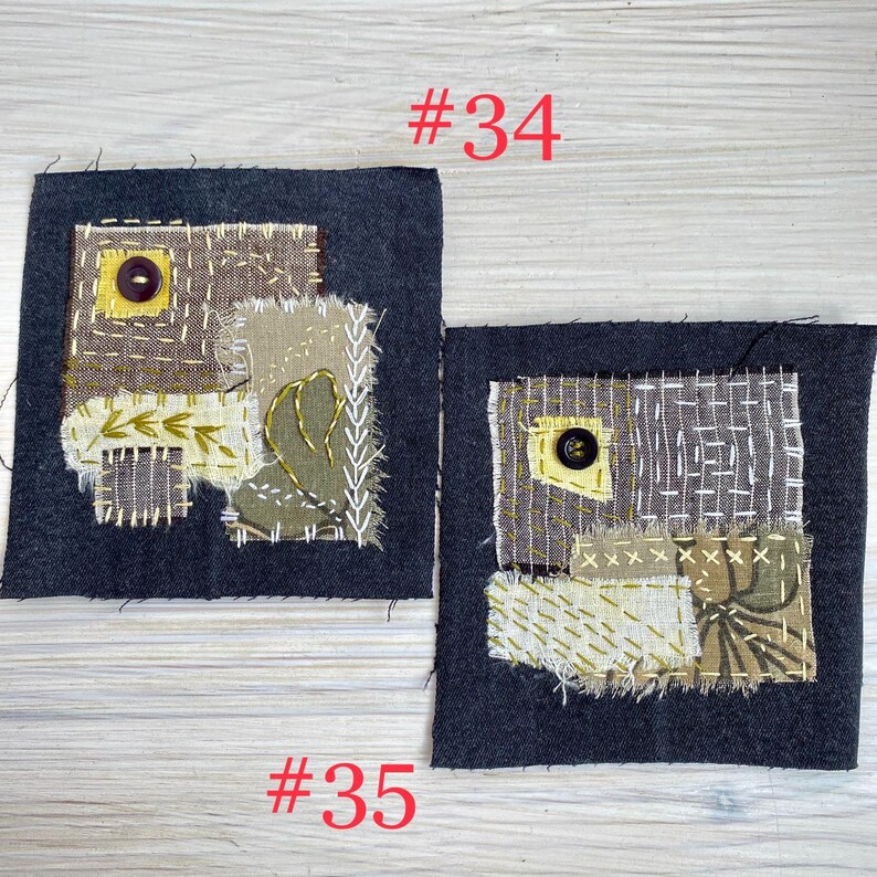 May include: Two square dark gray fabric patches featuring layered textile scraps in shades of brown, olive, and cream. Each patch includes visible hand-stitched embroidery, frayed edges, and a single dark button. The text #34 and #35 is visible.