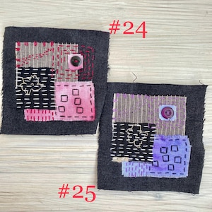 May include: Two square dark gray fabric patches featuring visible hand-stitched embroidery. Patch #24 displays pink and tan fabric squares with a black button. Patch #25 features purple and tan fabric squares with a purple button and white stitching.