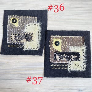 May include: Two square dark gray fabric patches labeled #36 and #37, featuring layered beige and black patterned textile scraps, visible white and yellow decorative running stitches, and a single black button sewn onto each piece.