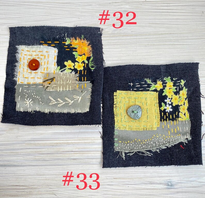 May include: Two square dark denim fabric patches labeled #32 and #33. Patch #32 features a white fabric square, a brown button, and yellow floral embroidery. Patch #33 features a yellow fabric square, a green button, and yellow floral embroidery.