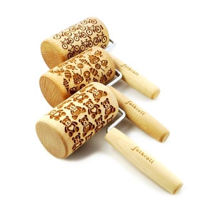 Può includere: Tre mattarelli in legno con diversi disegni incisi. I disegni includono biciclette, decorazioni natalizie e orsacchiotti. Ogni mattarello ha un manico in legno con la parola "Folkroll" incisa su di esso.