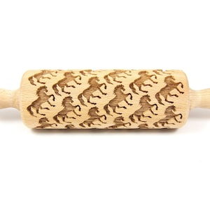 May include: A wooden rolling pin with a repeating pattern of horses engraved on the surface. The rolling pin is approximately 23 cm long and has a wooden handle with the word "Jolkroll" engraved on the side.