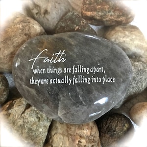 May include: A gray stone with the words "Faith when things are falling apart, they are actually falling into place" engraved on it.