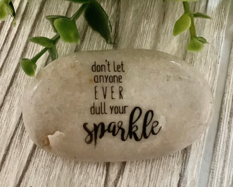 May include: A gray stone with the text "don't let anyone EVER dull your sparkle" written on it.