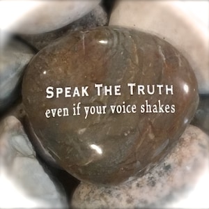 May include: A brown and gray stone with the words "Speak the truth even if your voice shakes" engraved on it.