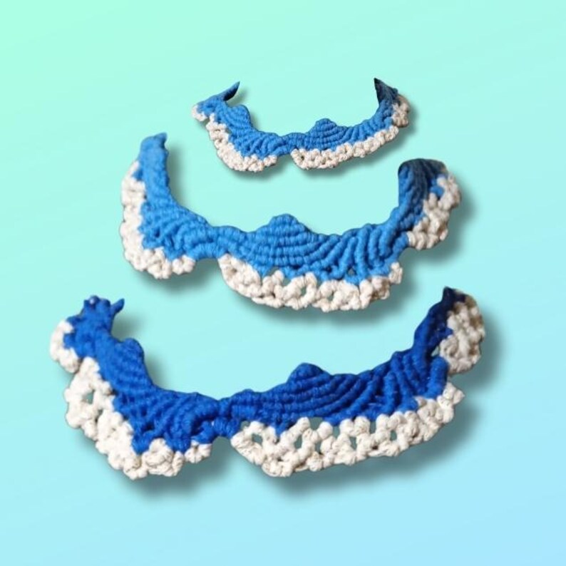 以下が含まれることがあります： さまざまなサイズの、手作りのかぎ針編みの襟が3つ。各襟は、鮮やかな青色の中心と対照的な白い縁を持つ波のようなデザインが特徴です。襟はグラデーションの青色の背景に表示されています。