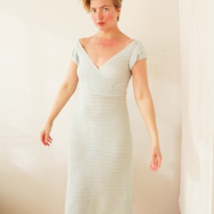 May include: A woman wearing a light blue crochet dress with a V-neckline and short sleeves.