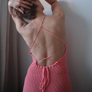 Peut inclure: Une femme portant une robe en crochet rose avec un dos croisé.
