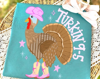 May include: A teal t-shirt featuring a graphic of a brown turkey wearing a pink cowboy hat and pink cowboy boots. The text "Turkin' 9-5" is printed in pink letters next to the turkey, accompanied by small pink star and sparkle icons.