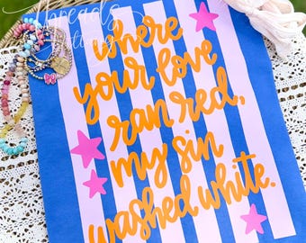Puede incluir: Un artículo de tela a rayas azules y rosa claro con texto naranja en cursiva que dice where your love ran red, my sin washed white. El artículo está decorado con cuatro estrellas de color rosa brillante e incluye pulseras de cuentas.