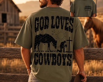 Puede incluir: Una camiseta de manga corta color verde oliva con un gráfico negro en la espalda que incluye el texto GOD LOVES COWBOYS, un caballo, un sol y una persona arrodillada ante una cruz. El pecho muestra un pequeño logo circular con el texto JOSHUA.