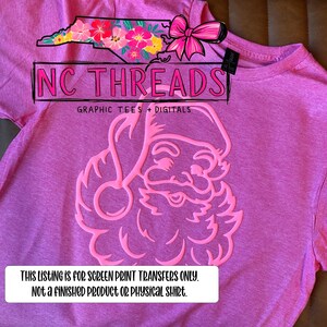 May include: A pink t-shirt featuring a Santa Claus design in a lighter pink hue. The shirt also displays the text "NC THREADS" and "GRAPHIC TEES + DIGITALS". A text box at the bottom states, "THIS LISTING IS FOR SCREEN PRINT TRANSFERS ONLY. NOT A FINISHED PRODUCT OR PHYSICAL SHIRT."