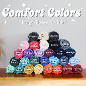 Puede incluir: Una variedad de camisetas de manga larga Comfort Colors enrolladas y dispuestas en forma de pir&aacute;mide. Los colores incluyen: Pimienta, Grafito, Sand&iacute;a, Blanco, Negro, Granito, Fruta de la pasi&oacute;n crujiente, Violeta, Orqu&iacute;dea, Baya, Azul marino, Medianoche, Abeto azul, Menta cremosa, Verde claro, Azul flo, Azul Lap&oacute;n, Vaquero azul, Chaum, Rojo isla, Espuma de mar, Mostaza, Mantequilla, Mel&oacute;n, Salm&oacute;n brillante, Carmes&iacute; y Ladrillo.