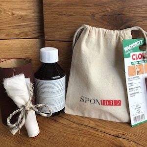 Könnte beinhalten: Ein Set Holzpflegeprodukte bestehend aus einer Flasche Holzpolitur, einer kleinen Tasche mit dem aufgedruckten Text "SPONHOLZ", einem Schleifpapierrollen und einem kleinen schwarzen Applikator mit dem aufgedruckten Text "WACHSSKITT schützt" und "CLOU FÜR HOLZ".