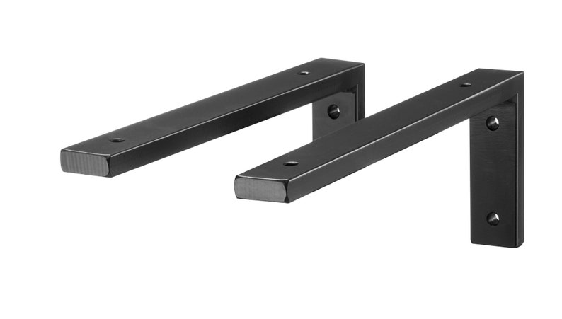 May include: Two black metal shelf brackets with rounded edges and multiple screw holes. The brackets are L-shaped and are designed to support shelves.