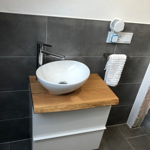 May include: White bathroom vanity with a wooden countertop and a white porcelain sink. A chrome faucet is attached to the sink. A white towel is hanging on a chrome towel rack.
