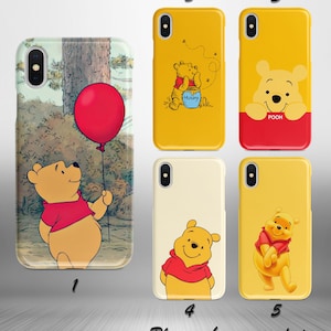 May include: Five different iPhone cases featuring Winnie the Pooh. The cases are yellow, cream, and a vintage-style image of Winnie the Pooh holding a red balloon. The cases feature different images of Winnie the Pooh, including Winnie the Pooh holding a jar of honey, Winnie the Pooh peeking out from behind a yellow background, and Winnie the Pooh standing with his arms crossed.