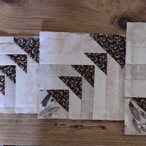May include: A set of five unfinished quilt blocks in various sizes. The blocks are made of white fabric with brown and white patterned fabric sewn into a geometric design.