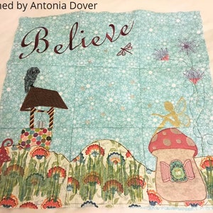 May include: A blue and green embroidered fabric wall hanging with the word "Believe" in cursive script. The design features a fairy, a well, and a mushroom house.