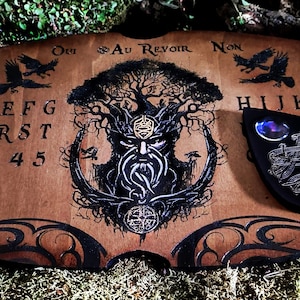 May include: A wooden Ouija board with a black and white illustration of a tree spirit. The board features the letters A-Z, numbers 1-9, and the words "Oui", "Yes", "No", "Au Revoir", and "Goodbye". A black heart-shaped planchette is included.