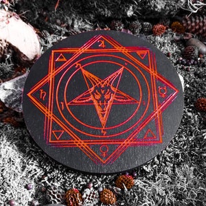 May include: A black wooden circle with a red pentagram and other symbols engraved on it. The circle is surrounded by moss and other natural elements.