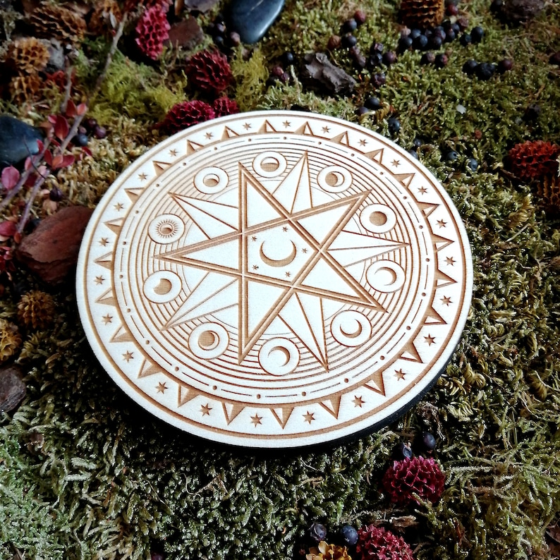 May include: A wooden circle with a carved design of a star with crescent moons around it. The circle is surrounded by a border of small stars.