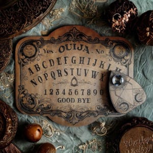 Può includere: Una tavola Ouija in stile vintage in legno, con l'alfabeto, i numeri e le parole "Sì", "No" e "Arrivederci". La planchette è un piccolo pezzo triangolare con una gemma trasparente. La tavola presenta elementi decorativi marrone scuro.