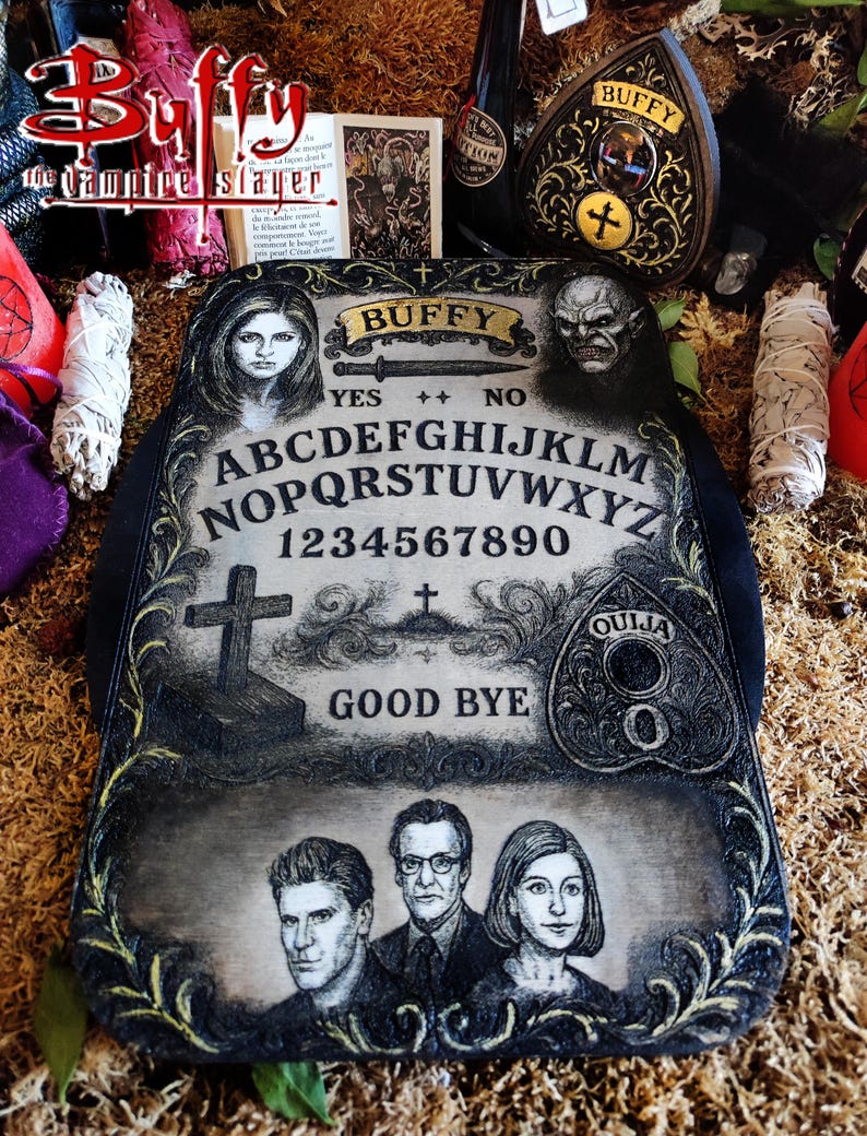May include: A decorative Ouija board featuring the Buffy the Vampire Slayer theme. The board has a black border and a distressed, aged appearance. It includes the alphabet, numbers, and the words "Yes," "No," and "Good Bye." The board also features portraits of characters.