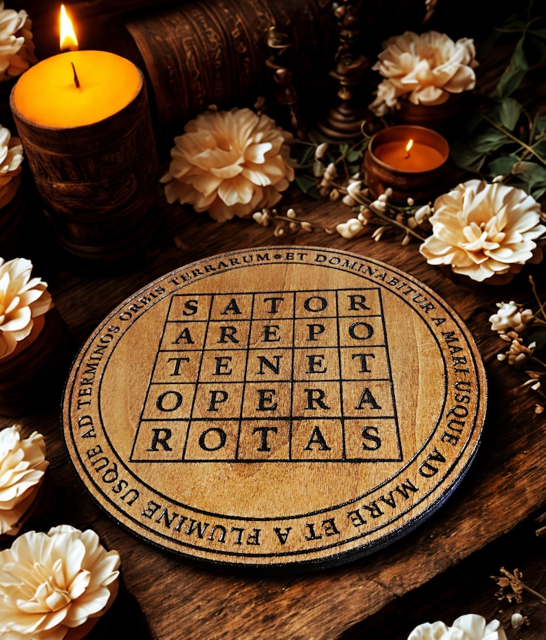 Puede incluir: Un posavasos de madera redondo con el dise&ntilde;o del Cuadrado Sator y texto. Est&aacute; sobre una superficie de madera, con velas y flores en el fondo. El dise&ntilde;o es negro sobre la madera natural. Se ven velas y flores.