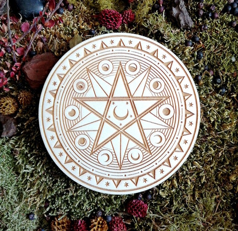 May include: A white wooden circle with a carved design of a six-pointed star with crescent moons and stars inside. The circle is surrounded by a border of stars and triangles.