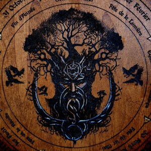 May include: A wooden circle with a tree of life design, featuring a bearded face in the centre. The circle is inscribed with text in French, including the names of the months and the equinoxes.