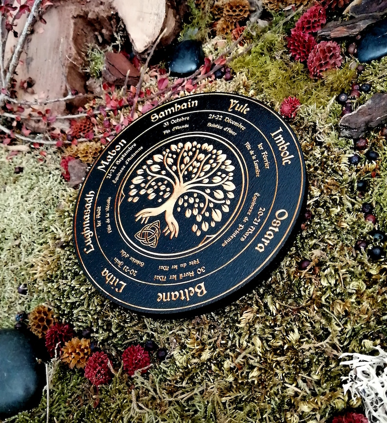 May include: A black wooden wheel with gold lettering and a tree of life design. The wheel is divided into eight sections, each representing a different Celtic holiday. The holidays are: Yule, Imbolc, Ostara, Beltane, Litha, Lughnasadh, Mabon, and Samhain.