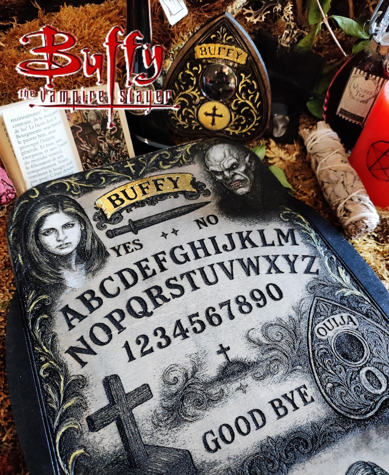 May include: A decorative Ouija board with the text "Buffy" and "Good Bye". The board features the alphabet, numbers, and a cross. Other items include a decorative heart-shaped plaque, a bottle, and a candle.
