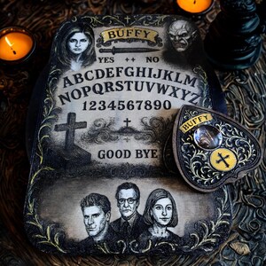 May include: A vintage-style Ouija board with the word "Buffy" at the top, featuring portraits and the alphabet. The planchette is heart-shaped with a cross. The board has the words "Yes", "No", and "Good Bye".